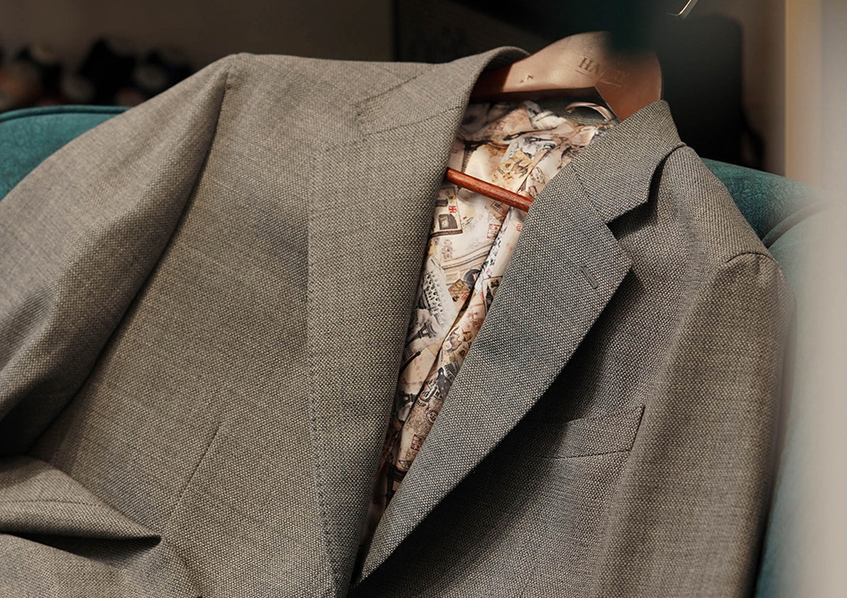 A wool-linen grey bespoke blazer laying on a sofa